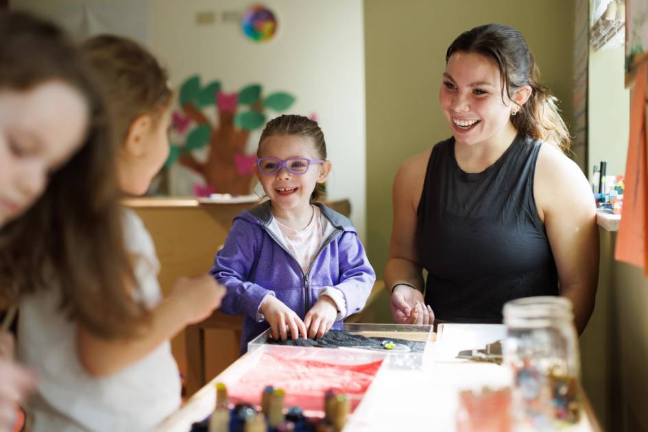 Students playing at a light table with an undergrad student