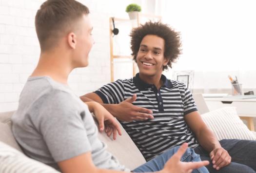 Two men conversing on a couch.