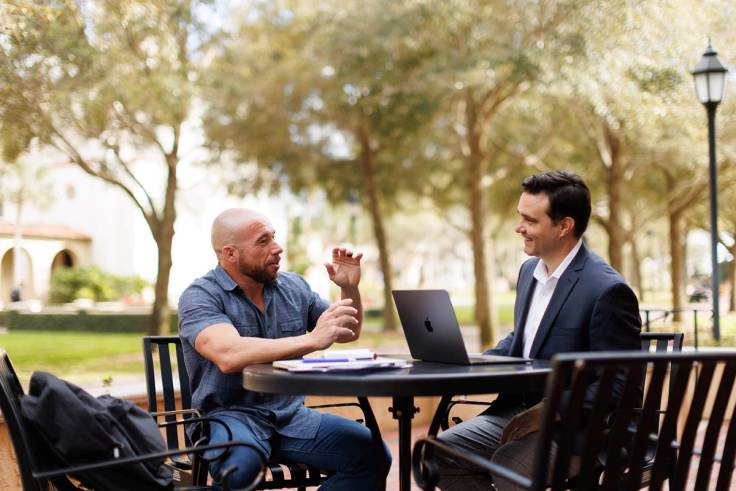 A professor and a student meet one on one on the Rollins College campus.
