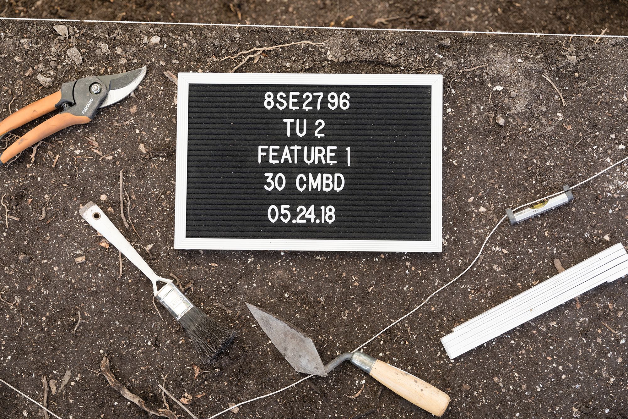 A photo from above of archaeological tools and sign on the dig site floor.