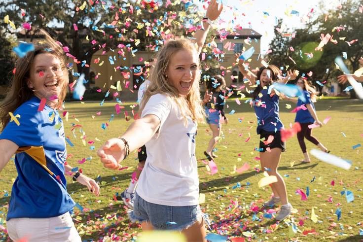 Students celebrate on campus with confetti. 