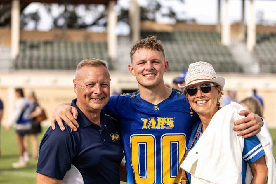 A Rollins student and their family pose on the Rollins College field. 