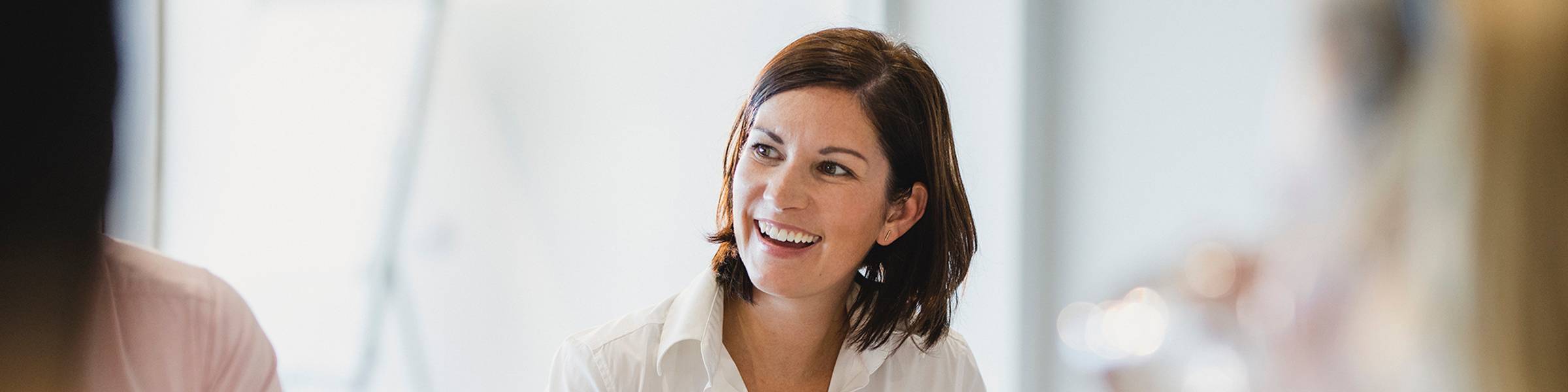 A businesswoman smiles during a group meeting.