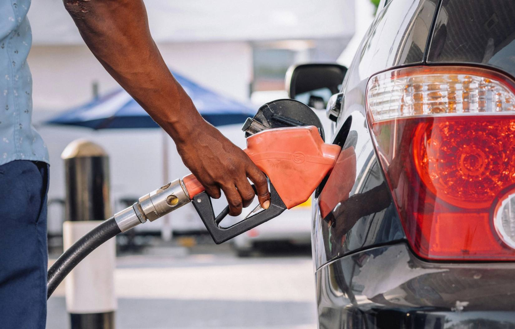 hand pumping gas into a car at a station