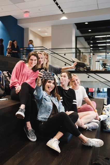 A group of college students taking selfies on the atrium stairs.