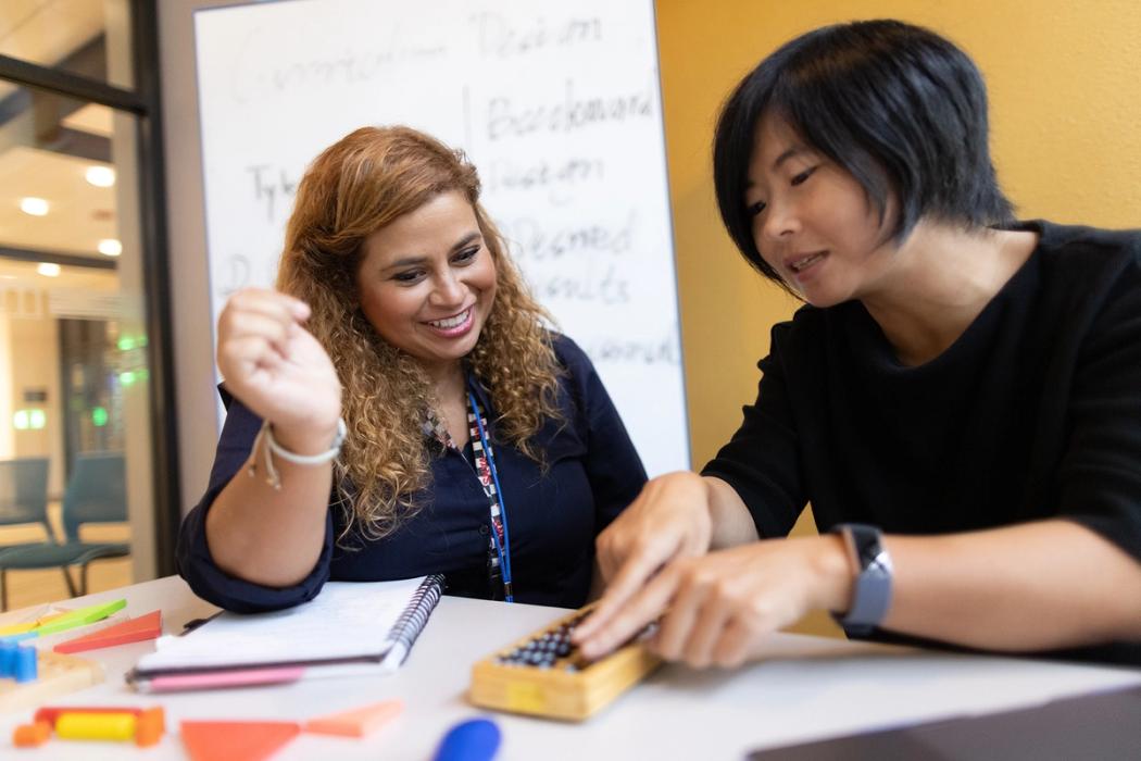 A professor demonstrates how to use a teaching tool with a student teacher.