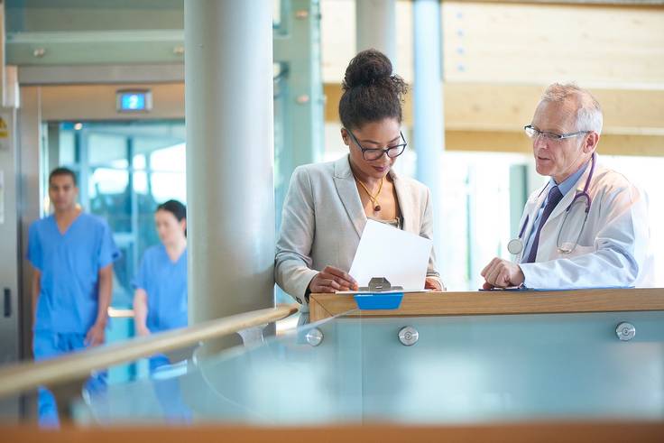A healthcare administrator meets with a doctor.