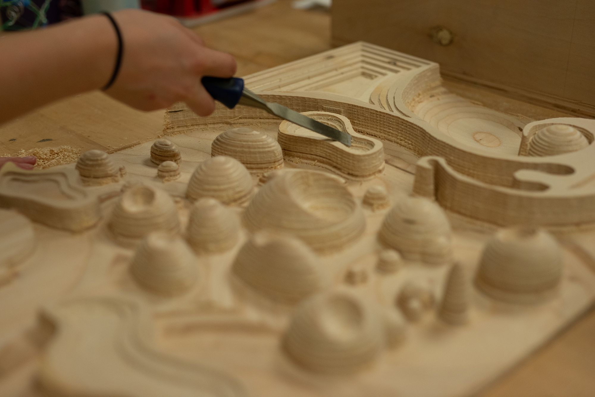 A student using a chisel to clean up a CNC milled project.