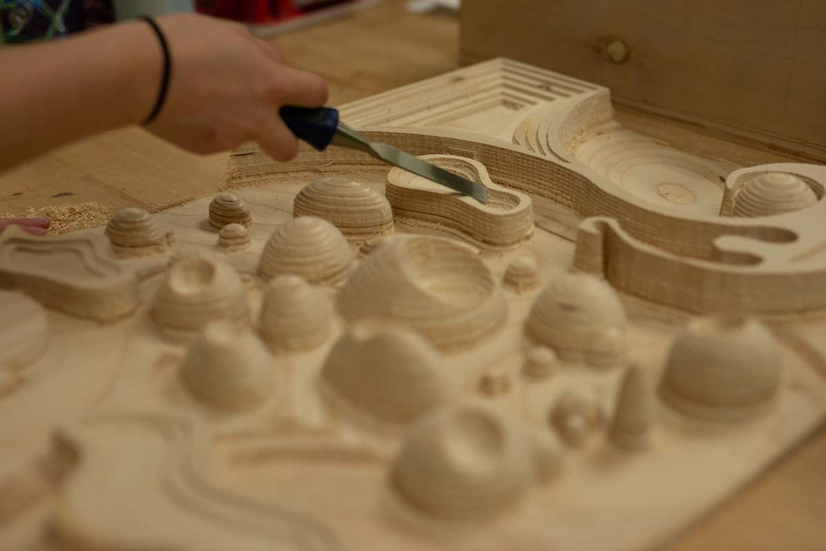 A student using a chisel to clean up a CNC milled project.