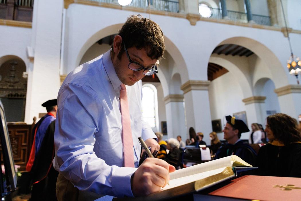 A student signs the official registry of the Theta Chapter of Phi Beta Kappa.