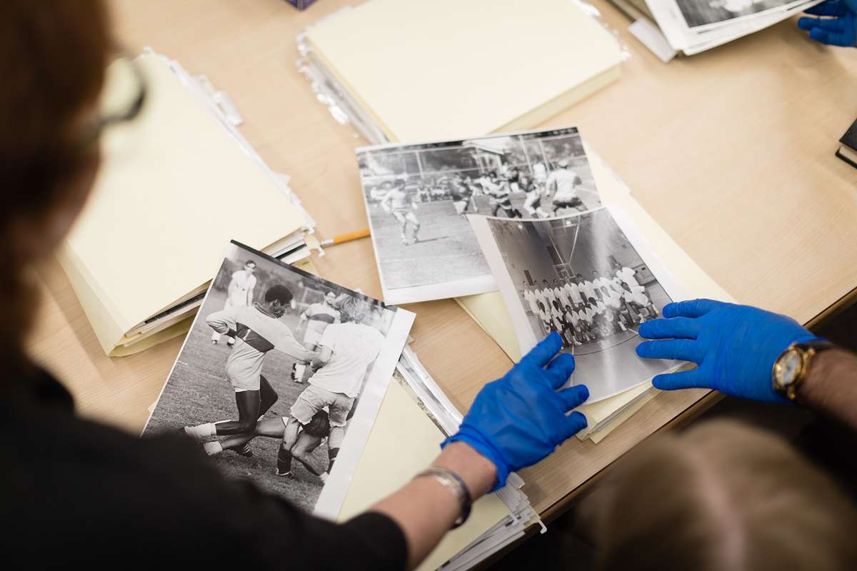 Professor Claire Strom and college American History student are looking at archived athletics photos.