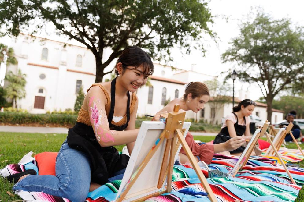 A student paints a watercolor painting outside on Fox Day 2022.