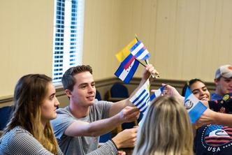 Spanish professor passing out Latin American flags in class to students.