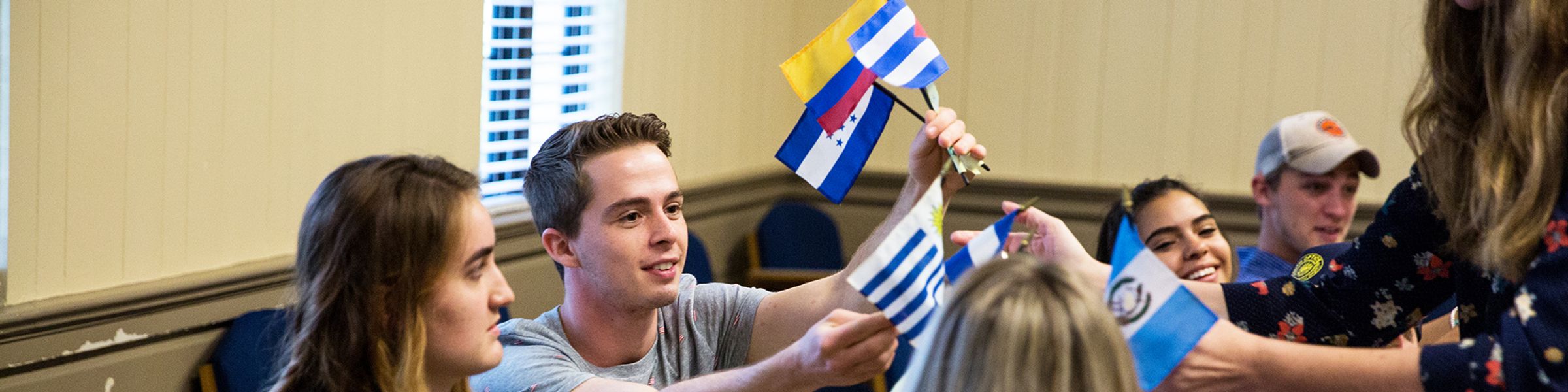 Spanish professor passing out Latin American flags in class to students.