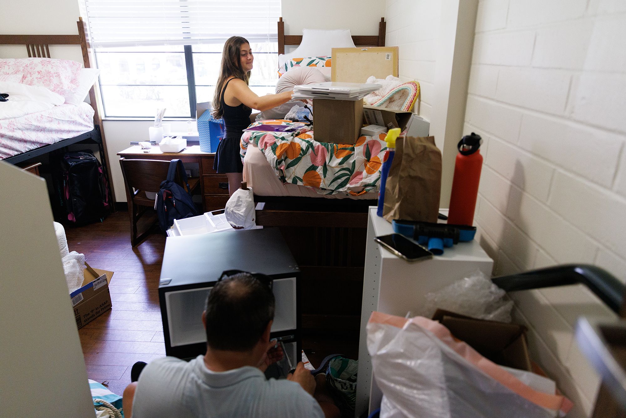 A father helps his daughter move into her college dorm room.