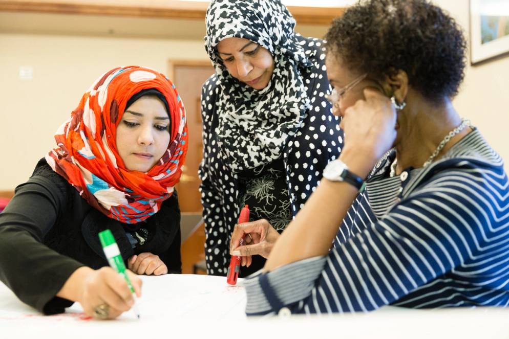 Three students in the Global Links Initiative work together in an office.