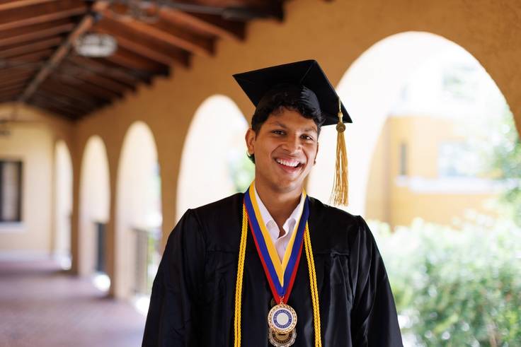 A Rollins student smiling in their cap and gown at graduation. 
