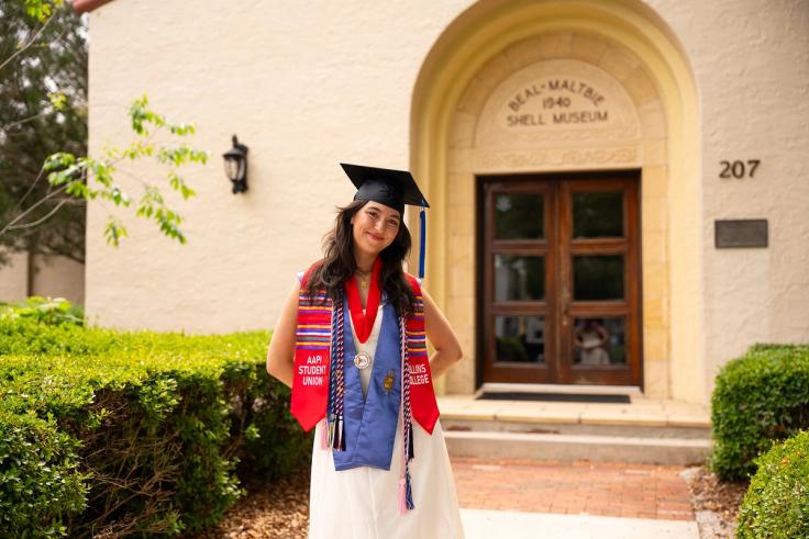 Sydney Boswell in graduation regalia on Rollins campus.