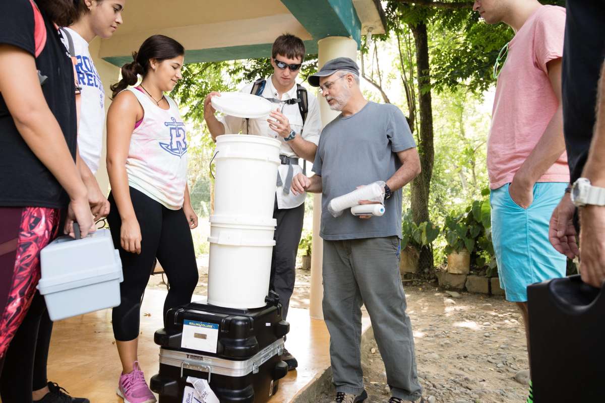 A professor and a group of students prepare a water filtration system.