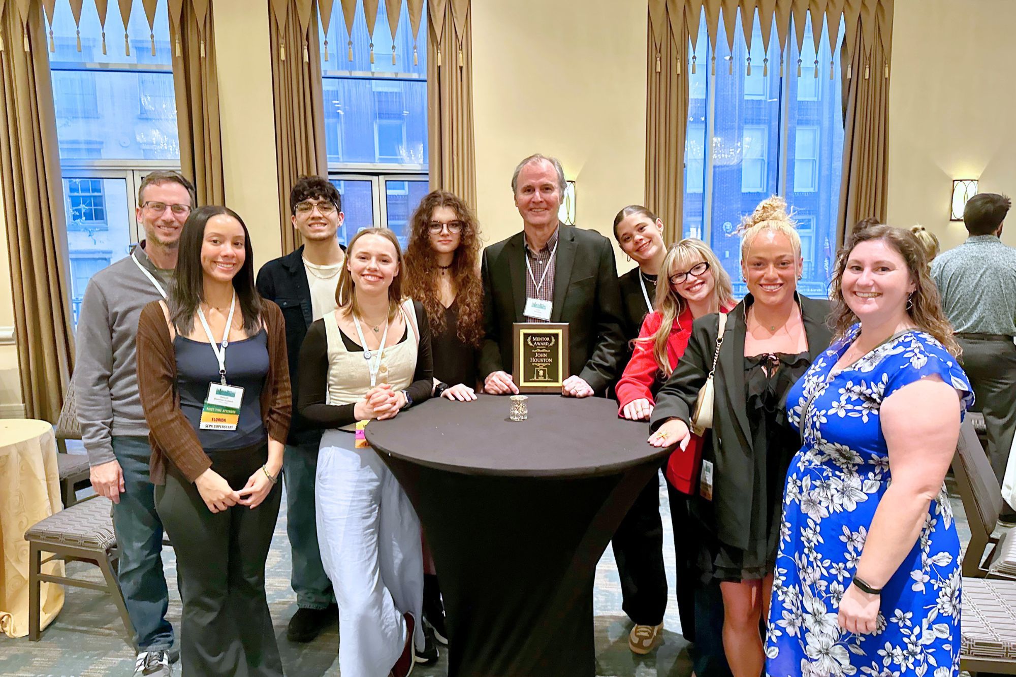 Psychology professor John Houston posing with his award alongside Rollins students