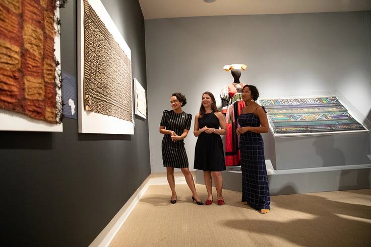 Two students and their professor admire their African art exhibition at the Cornell Fine Arts Museum.