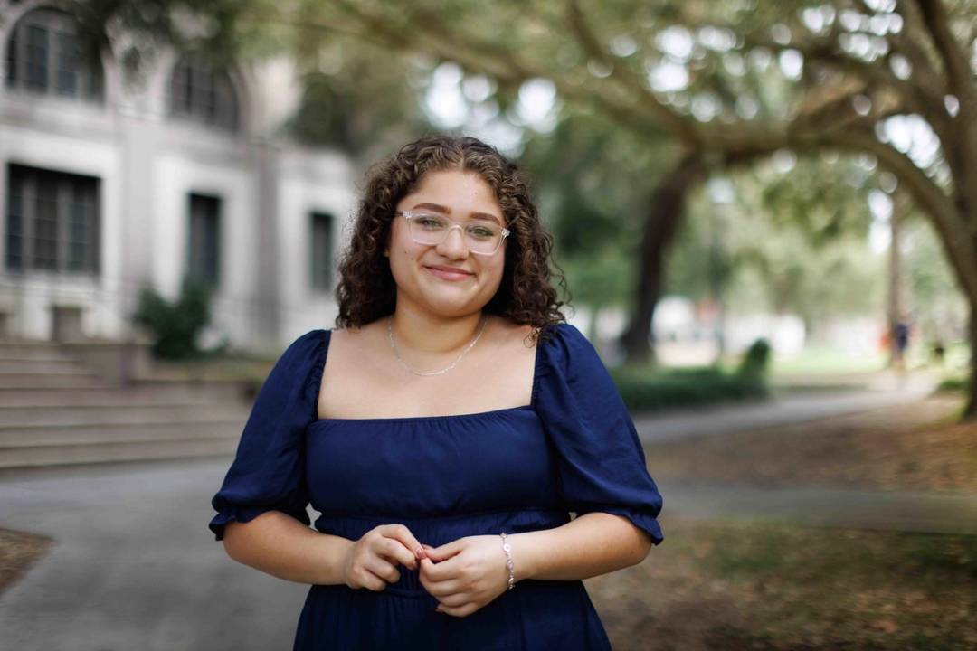 Photo of female student in blue dress standing on Rollins campus.