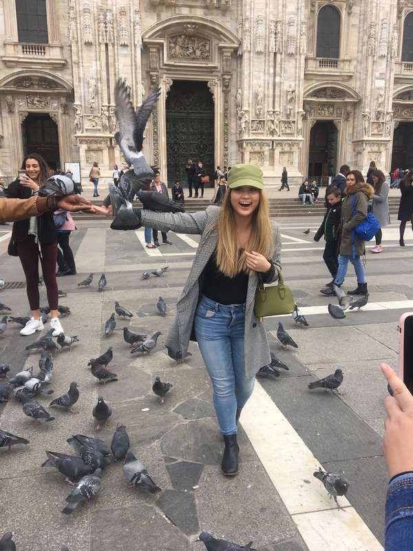 Rollins student crosses a square in Venice, Italy, full of pigeons.