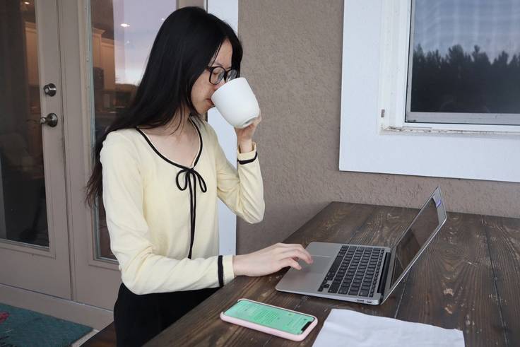 Jean Zhang ’20 sips coffee while working on her laptop during a virtual internship with Australia-based Functional Health and Performance.