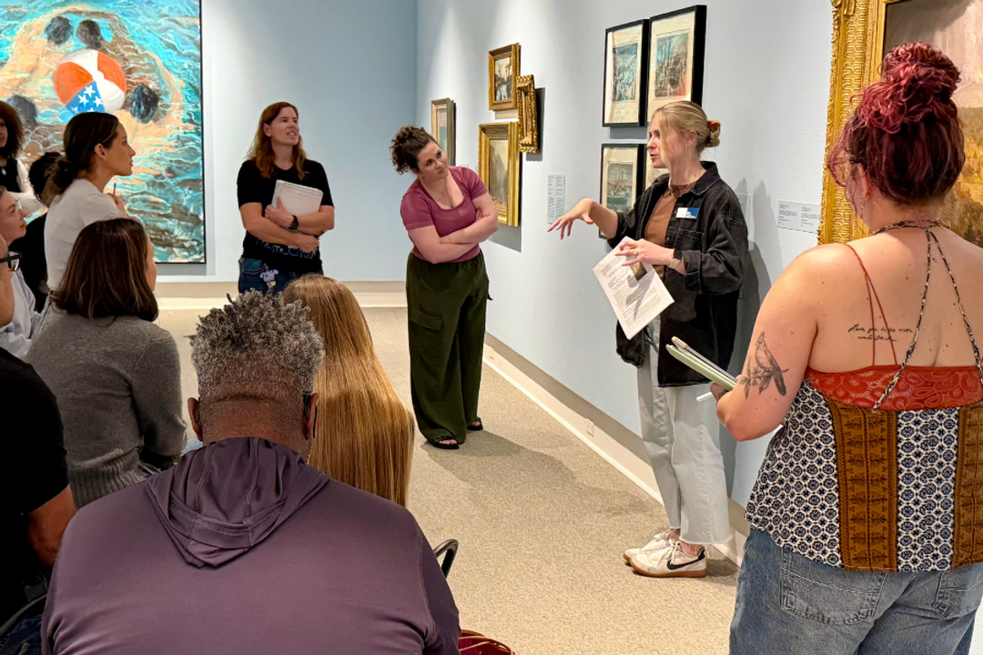 Museum guide discusses artwork with visitors in a gallery.
