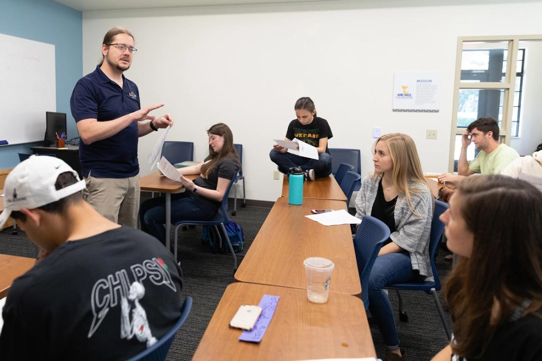 Professor Matthew Forsythe speaking to his class of students sitting at their desks.