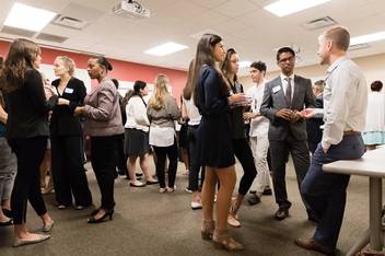 A group of students dressed in business attire talking and networking.