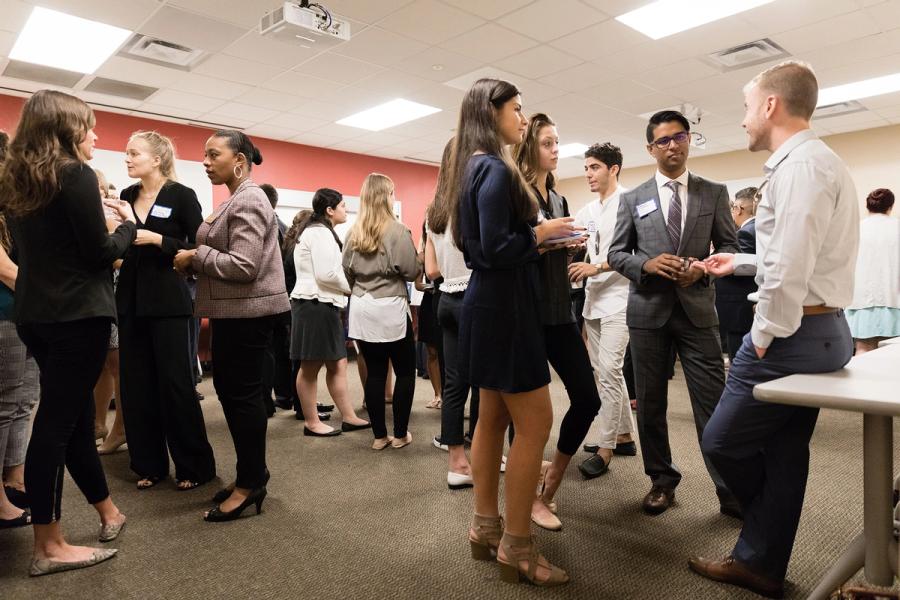 A group of students dressed in business attire talking and networking.