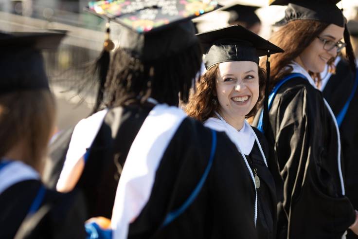 A female graduate smiles during a commencement ceremony.