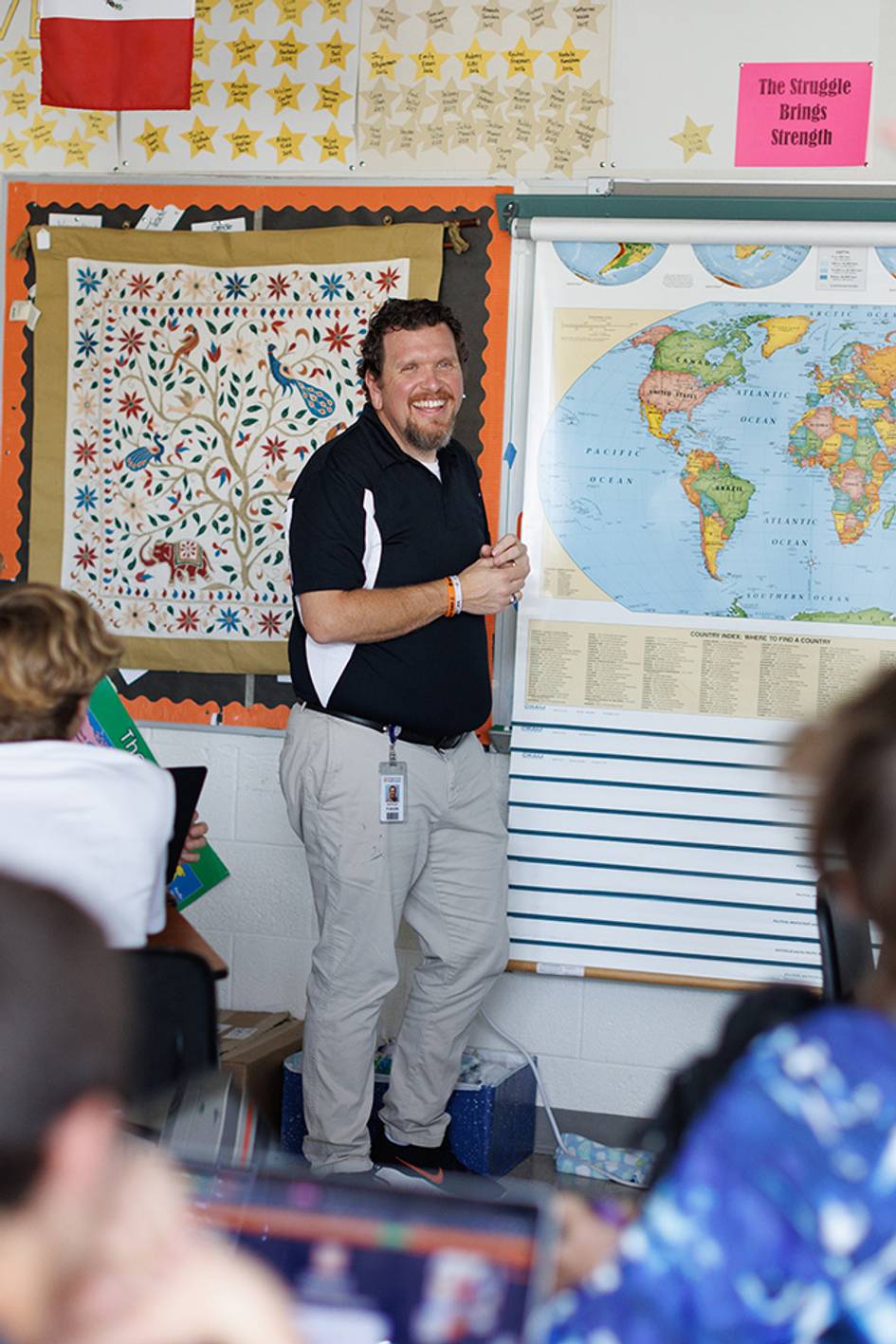 A middle school teacher smiles while engaging with his class.