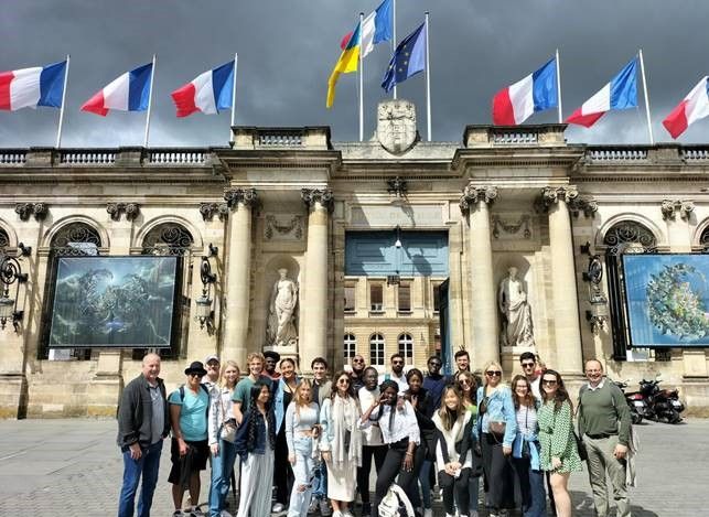 Group of Rollins students in front of building with French flags overhead.