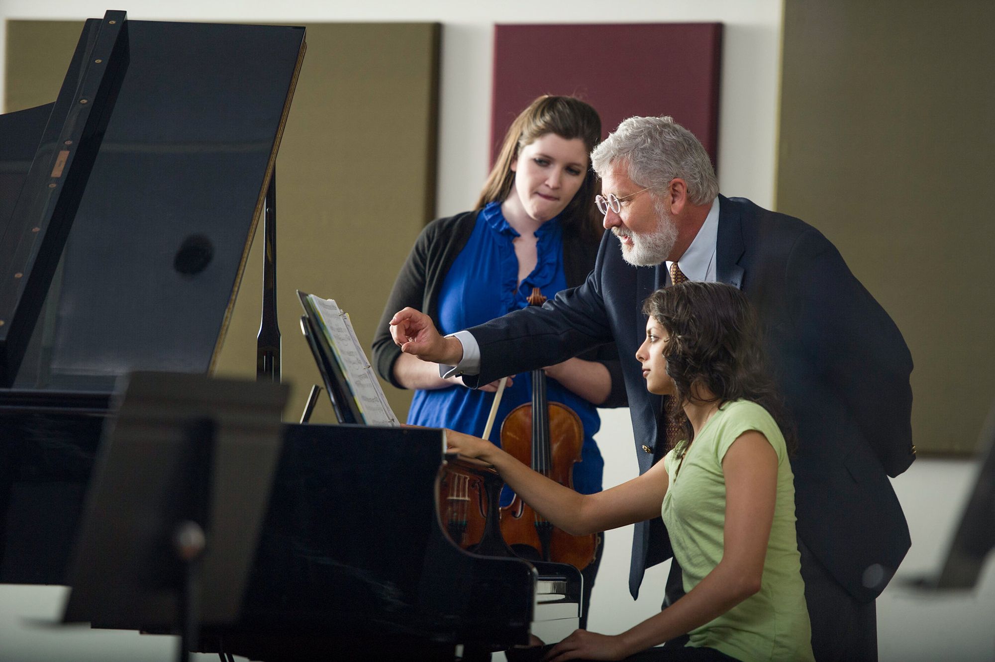 Rollins students on piano and on a violin working with professor John Sinclair