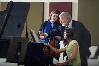 Rollins music professor John Sinclair instructs students at a piano.