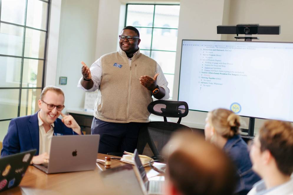 Eltavious Johnson ’26 leading an engaging SGA meeting with student leaders around a conference table.