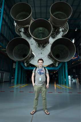 A college student standing proud in front of a NASA rocket.