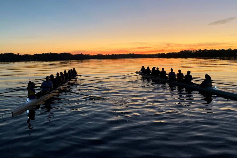 Two crew teams rowing at sunset.