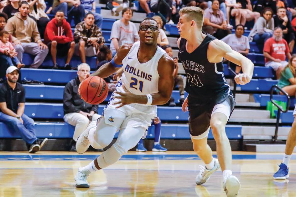 Rollins basketball game, student dribbling and passing an opponent 