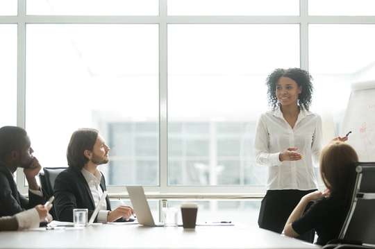 A business professional gives a presentation to an executive team.