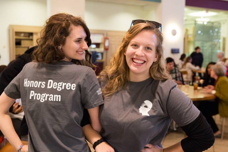 Two Rollins College students wearing honors degree program shirts.