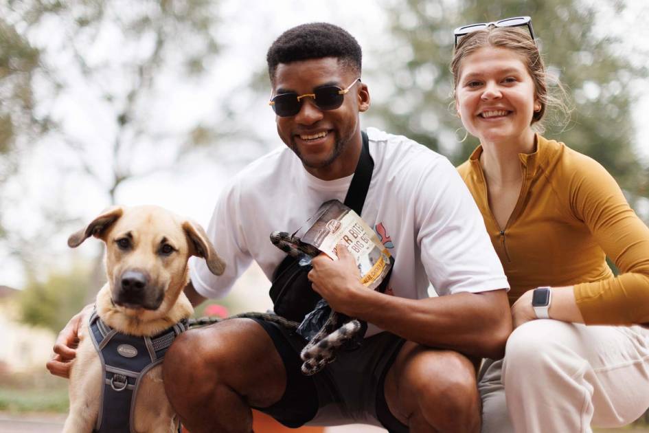 Two students pose with their dog on campus.