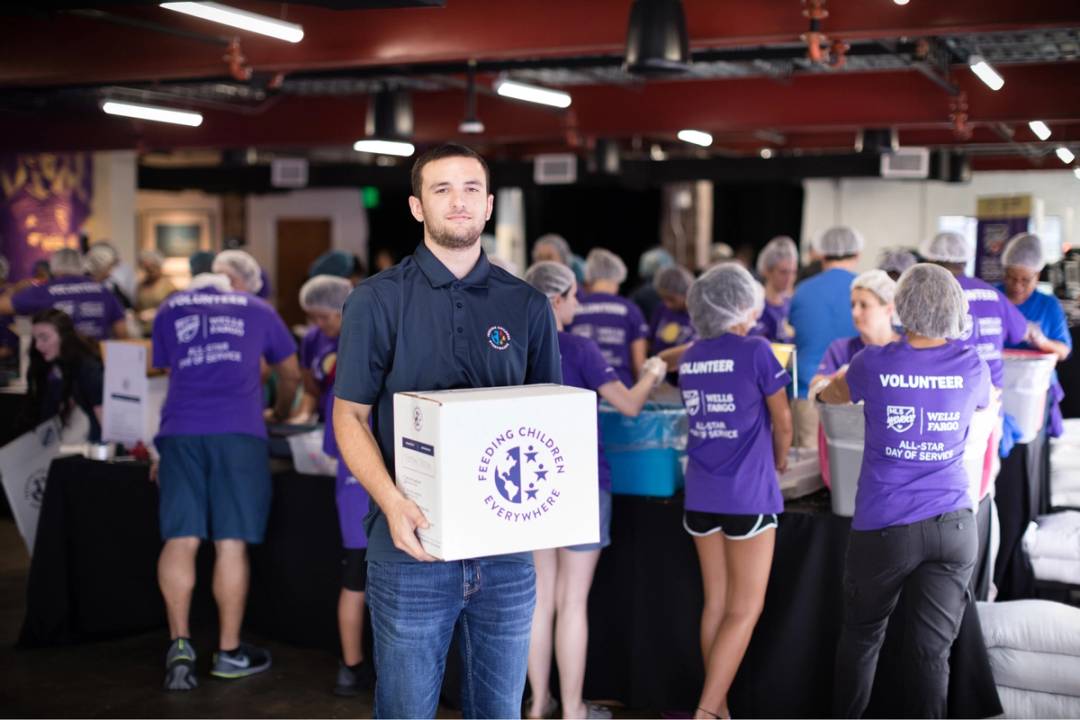 A student holds a box of food during a community service event.