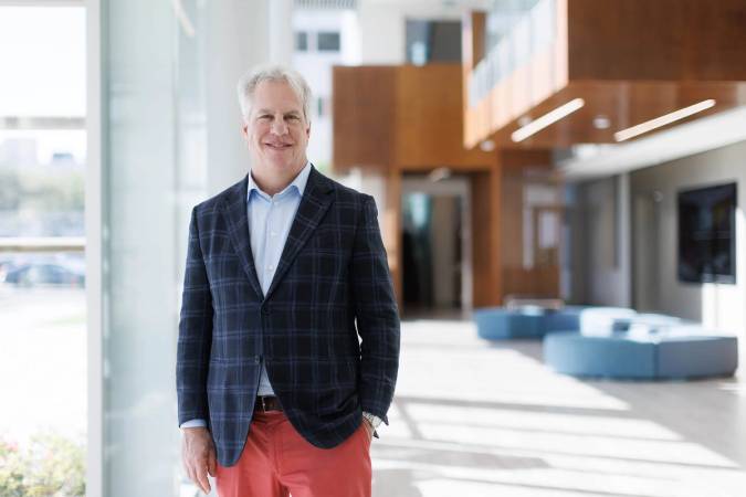 Sam Hocking poses for a portrait in the lobby of an office building.