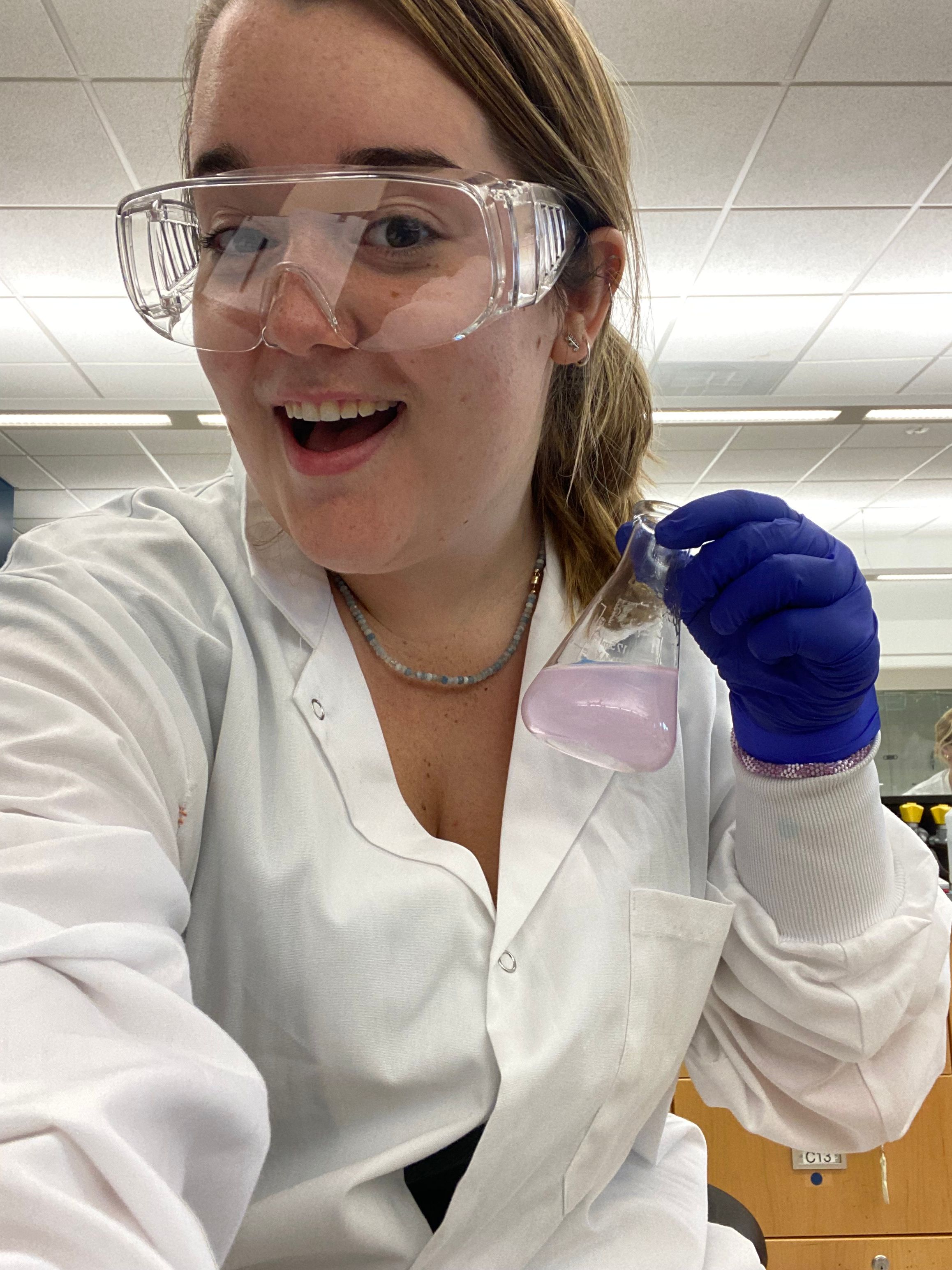 Student holding glass bottle in lab.