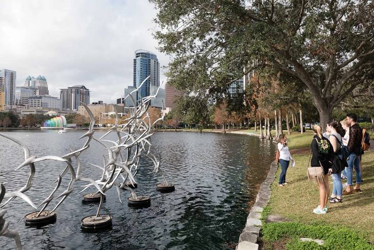 A professor talks to a group of students about an art installation in Lake Eola.