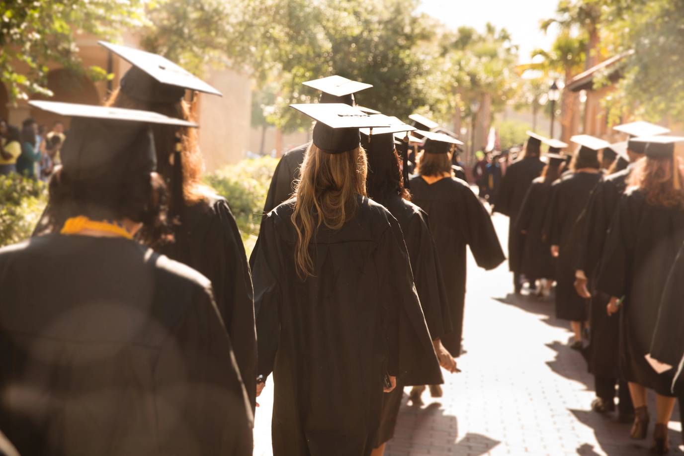 Students in gaps and gowns walk to commencement at Rollins College, one of the best colleges for transfer students.