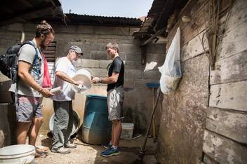 A professor and two students prep a water filtration system.